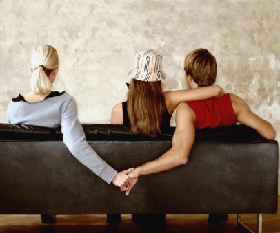 two people embracing on a sofa, with one person holding hands with a third behind the second's back